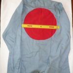 back of blue denim shirt with large solid red circle of fabric attached