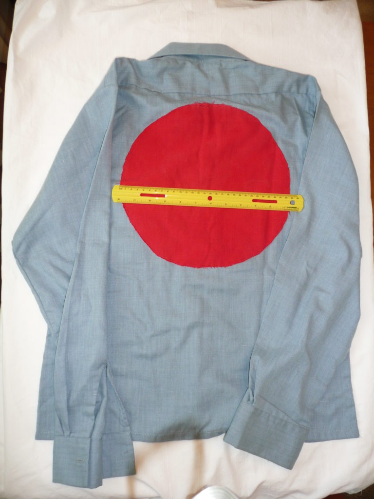 back of blue denim shirt with large solid red circle of fabric attached